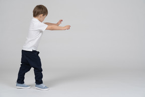 Side view of little boy walking with his hands extended forward