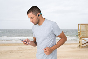 A man standing on the beach looking at his cell phone