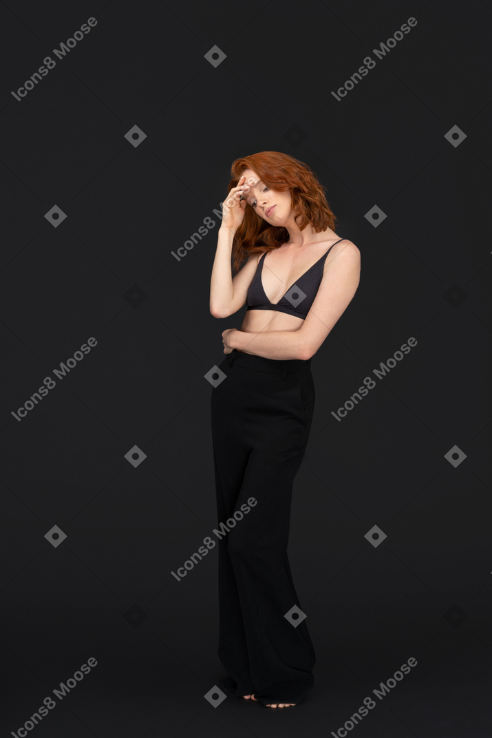 A frontal view of the cute red haired girl posing on the black background with the eyes closed