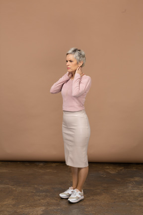 Vista laterale di una donna in abiti casual in piedi con le mani dietro la testa