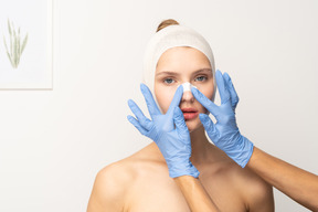 Paciente do sexo feminino com as mãos colocando gesso no nariz