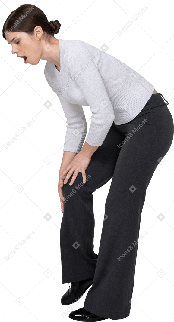Vista laterale di una giovane donna in abiti da ufficio che tocca il ginocchio