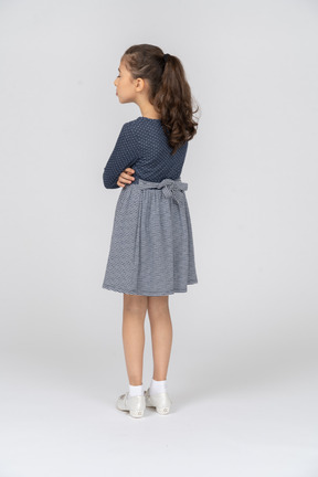 Three-quarter back view of a girl standing with folded hands