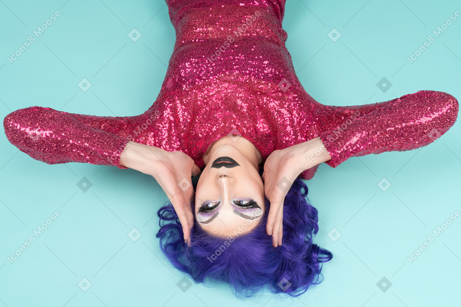 Drag queen in pink dress lying on the floor & holding their face