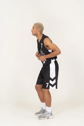 Side view of a surprised young male basketball player touching stomach