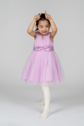 Little girl in pink dress making horns with fingers