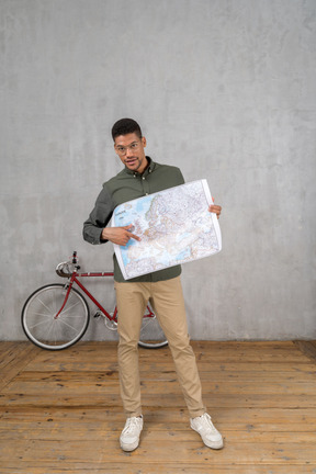 Front view of a man holding and pointing at a map