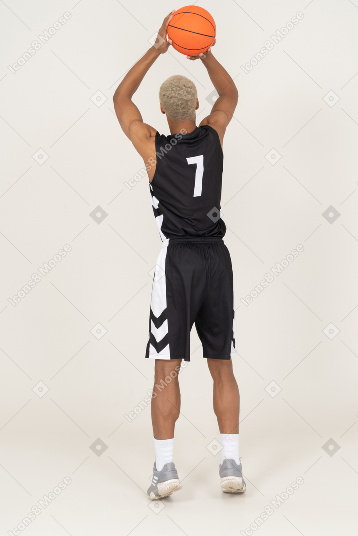 Back view of a young male basketball player throwing a ball