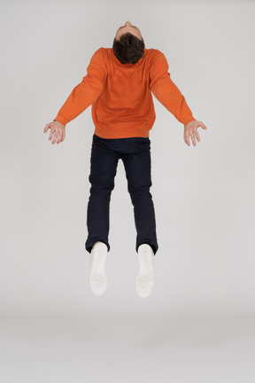 Junger mann im orange sweatshirt springen