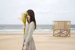 A woman holding a bunch of flowers on a beach
