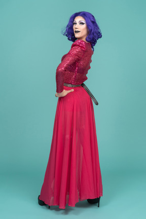 Porträt einer drag queen in rosafarbenem kleid, die lächelt, während sie über die schulter schaut