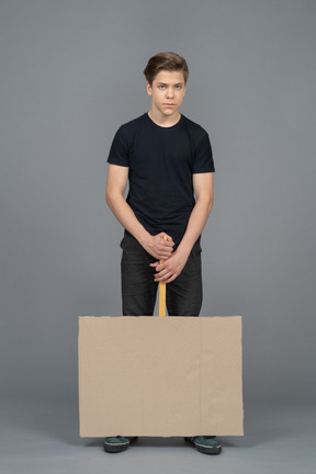 Serious young man holding a poster upside down