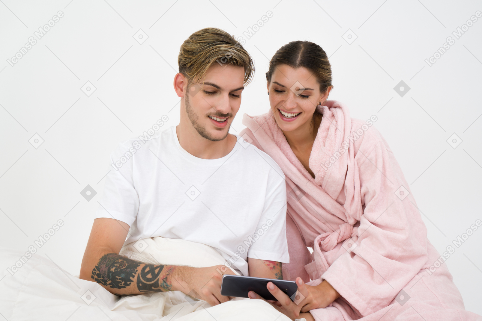 Couple assis dans son lit et regardant smartphone