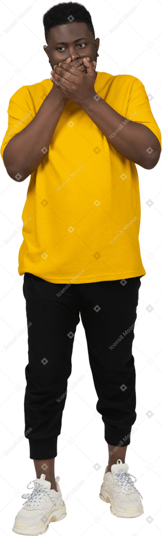 노란색 티셔츠를 입은 어두운 피부의 충격을 받은 젊은 남자의 전면 모습