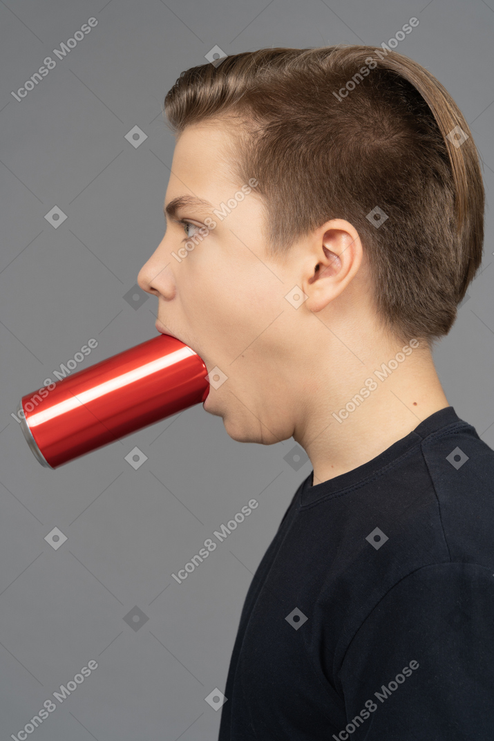 Side view of a man with red can in his mouth