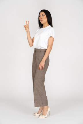 Three-quarter view of a young woman in breeches showing peace sign