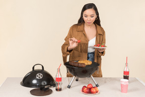 Joven mujer asiática haciendo una barbacoa y sosteniendo un plato de fresas