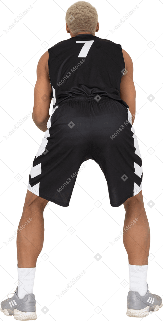 Вид сзади молодого баскетболиста мужского пола, держащего мяч