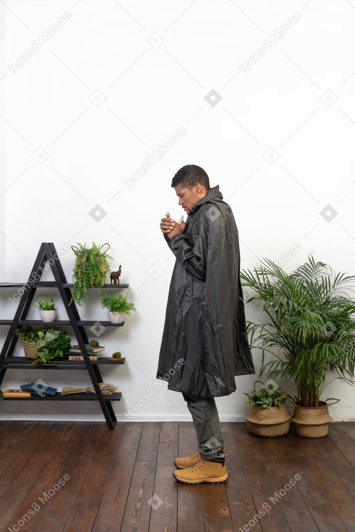 Side view of a man trying to warm up with hot tea