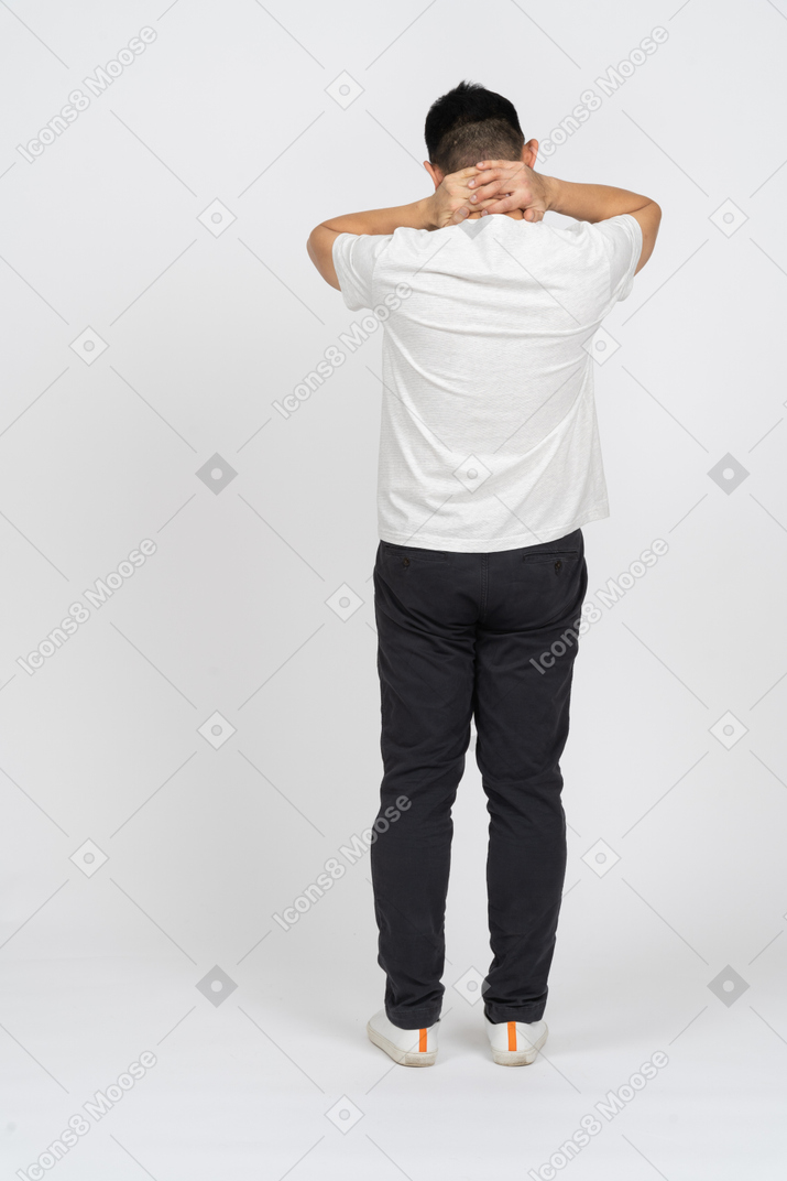首に手を置いて立っているカジュアルな服装の男性の背面図