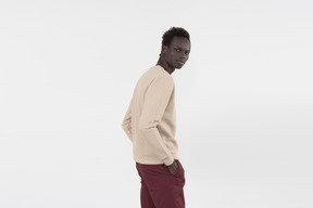 A young black man in a grey sweater standing alone on the white background