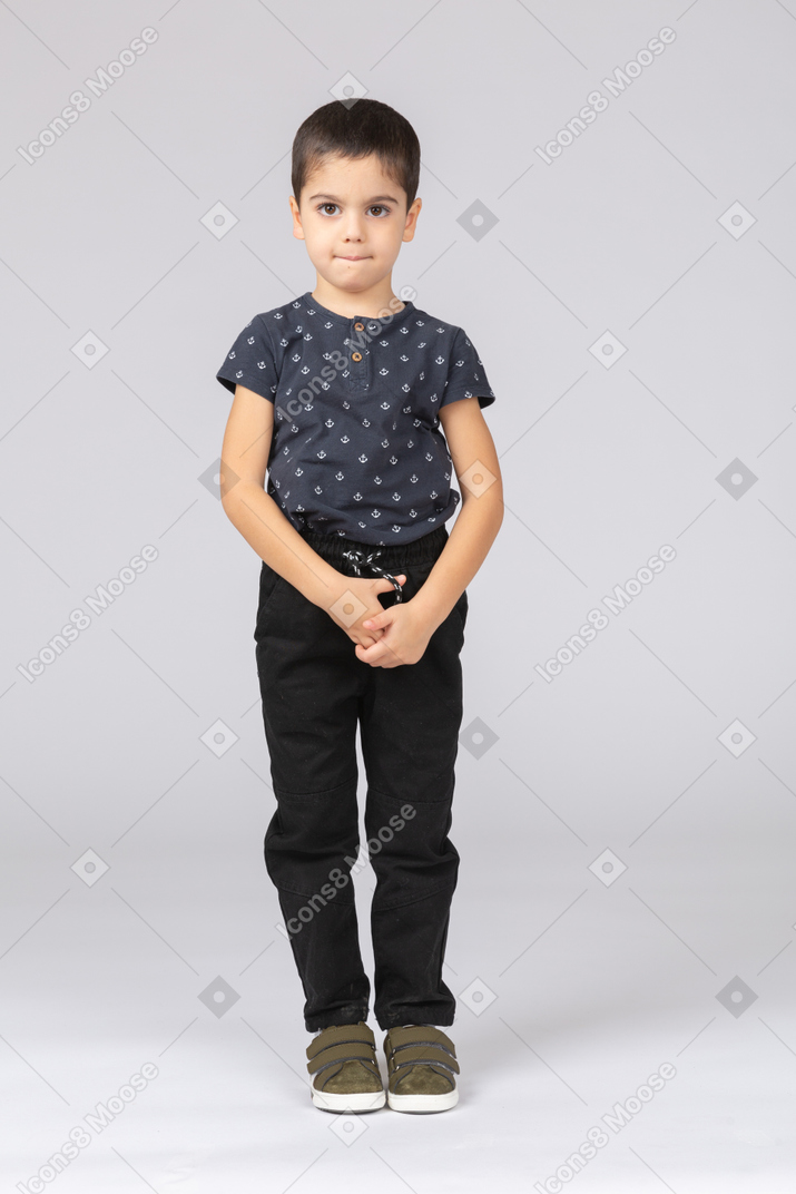 Front view of a shy boy in casual clothes looking at camera
