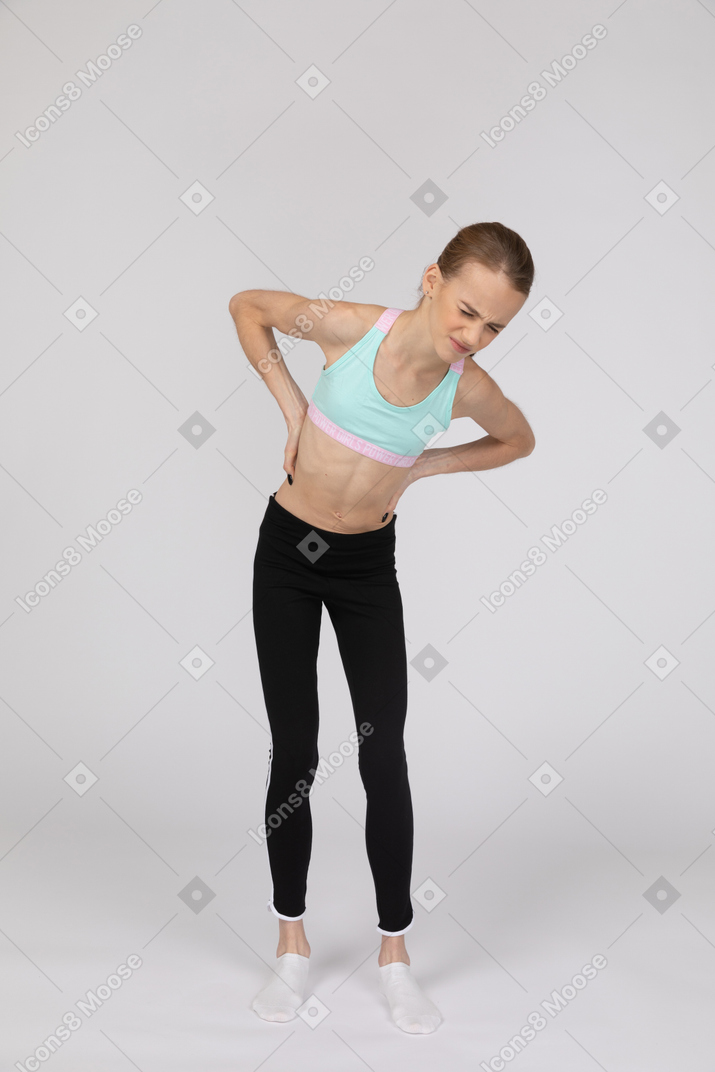 Una adolescente en ropa deportiva que sufre de dolor.