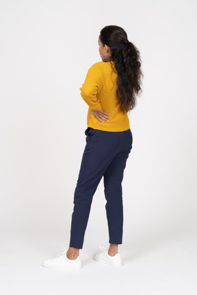 Rear view of a girl in casual clothes posing with hand on hip