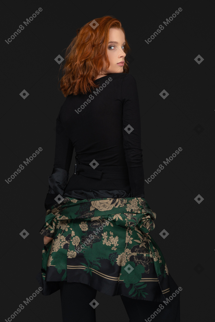 Standing back to camera young woman taking jacket off