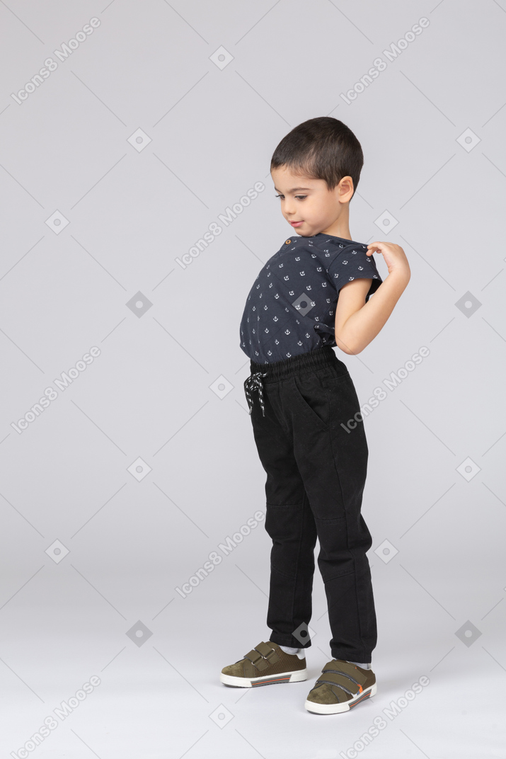 Vista lateral de um menino com roupas casuais, alongamento com as mãos nos ombros