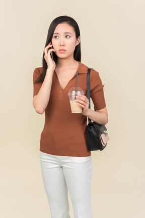 Sad looking young asian girl talking on the phone
