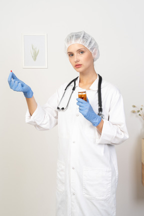 Three-quarter view of a young female doctor offering a pill