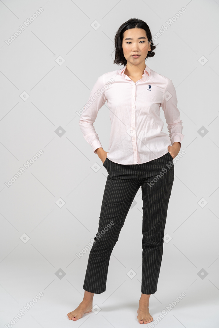 Женщина в офисной одежде позирует с руками в карманах