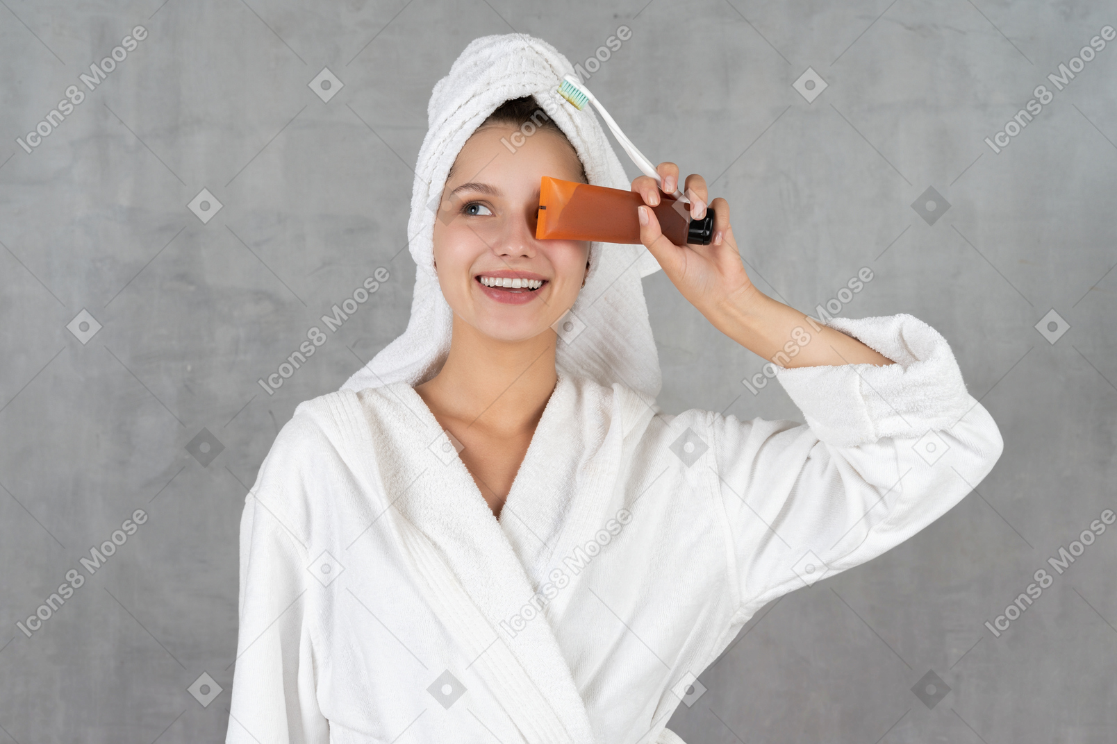 Woman in bathrobe smiling while holding tube over eye