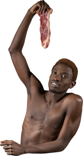 Vista frontal de un joven afro sosteniendo una rebanada de carne