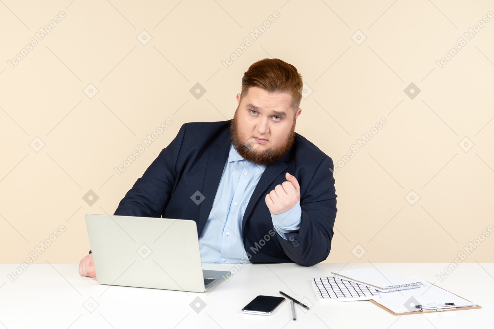 Молодой офисный работник с избыточным весом сидит за столом со сжатым кулаком