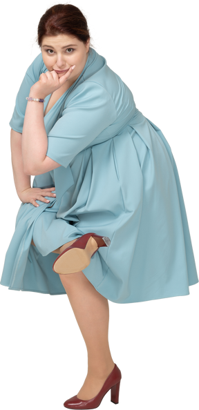 Женщина в синем платье балансирует на одной ноге, вид спереди