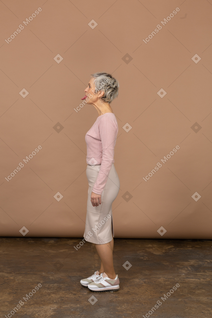 一个穿着休闲服的女人的侧视图，露出舌头