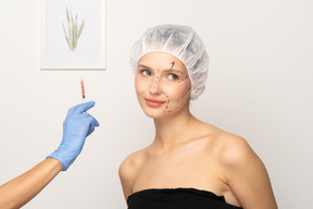 Cheerful young woman and hand holding syringe