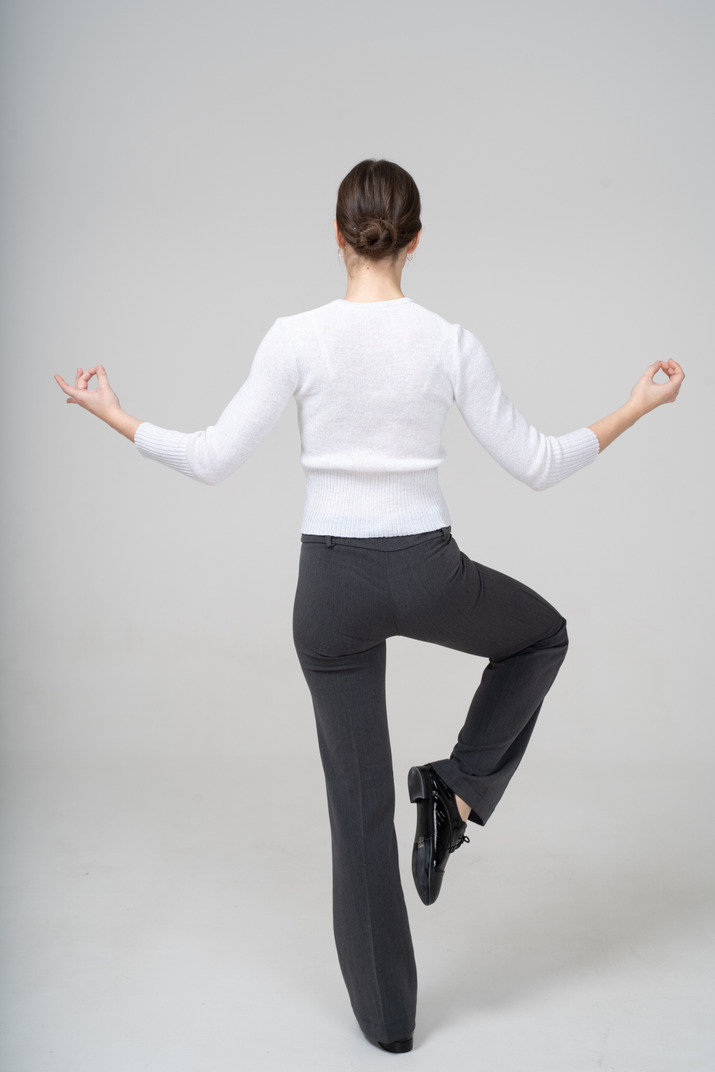 Rear view of a young woman in suit doing yoga