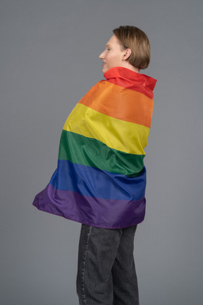Side view of young man wrapped in rainbow flag