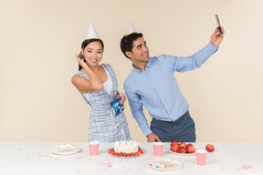 Joven pareja interracial haciendo una selfie mientras celebra cumpleaños