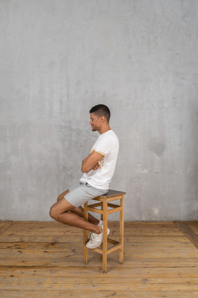 Vista lateral del hombre sentado con los brazos cruzados