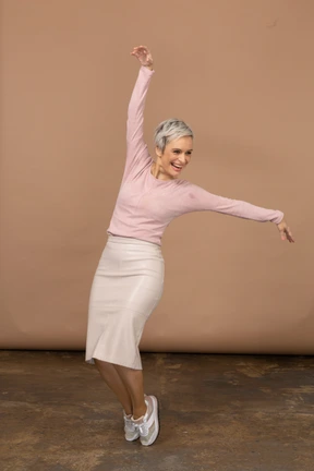 Front view of a happy woman in casual clothes standing on toes