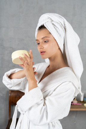 Mujer en bata de baño aplicando crema de manos