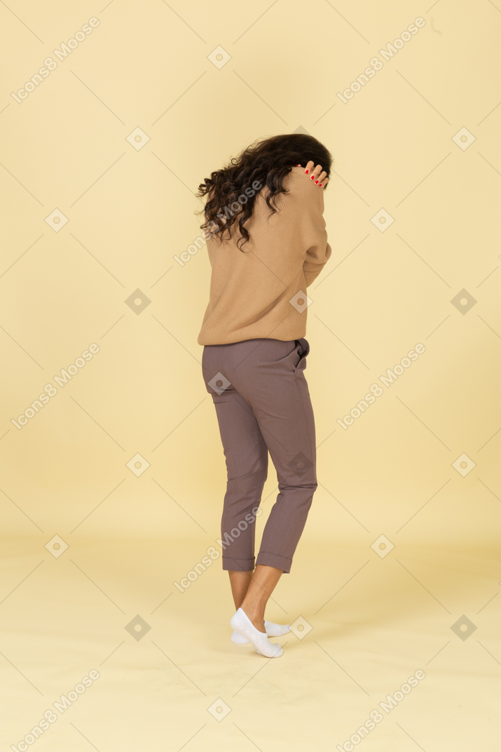 Три четверти сзади замкнутой темнокожей молодой женщины, обнимающей себя