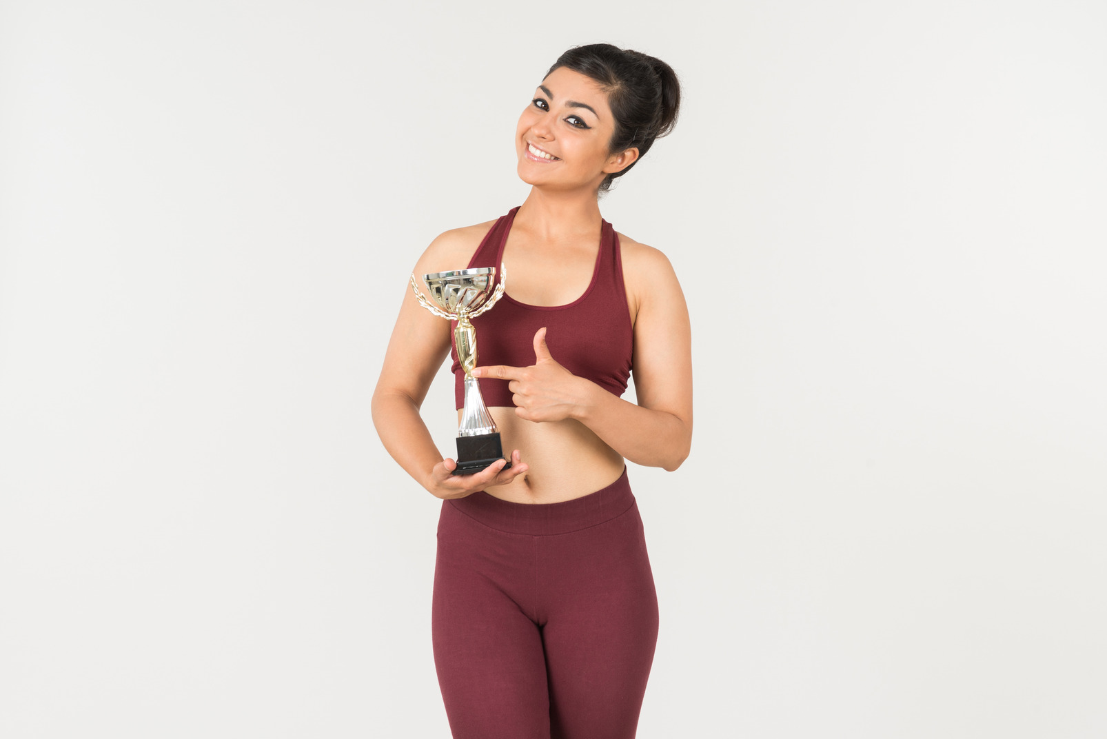 Young indian woman in sporstwear pointing at award she's holding