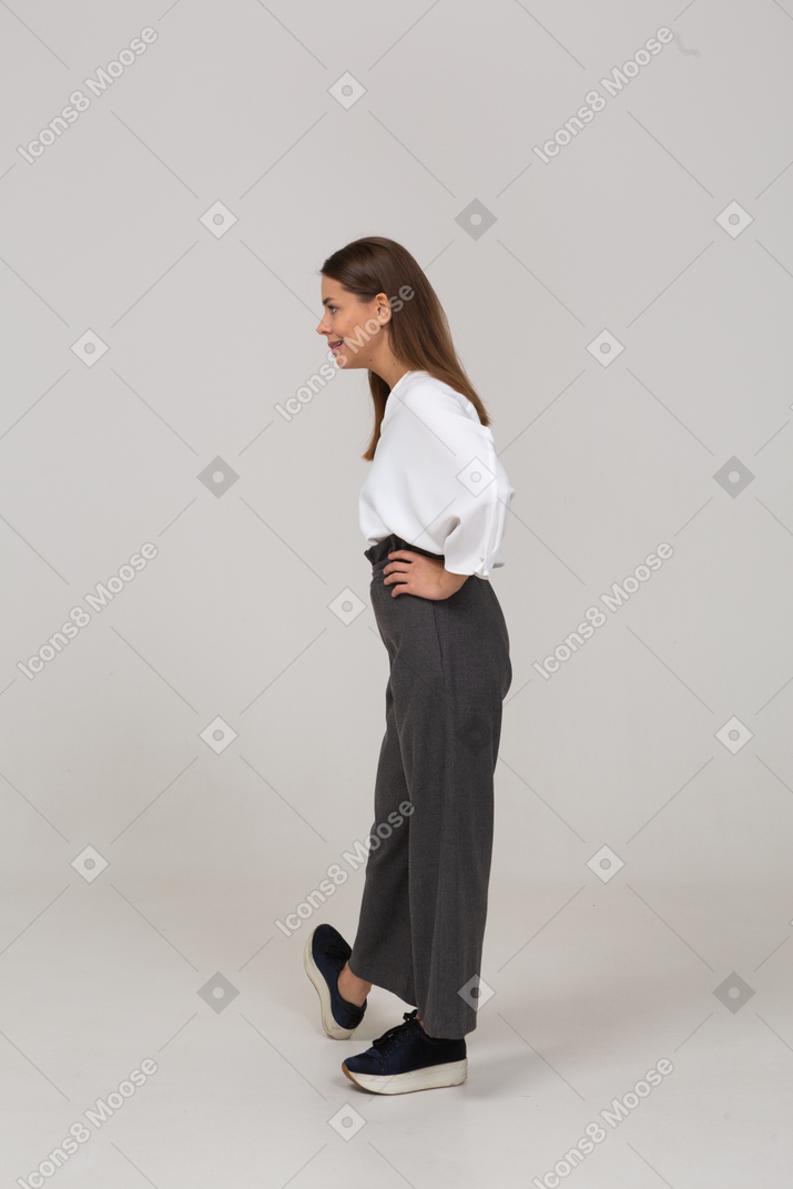 Vista lateral de uma jovem arrogante com roupa de escritório colocando as mãos nos quadris