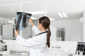 Женщина-врач смотрит на рентгеновский снимок