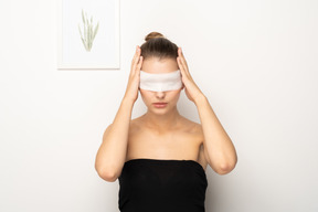Woman with eye bandage holding her head